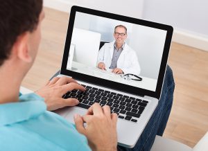 Man having video chat with doctor on laptop at home